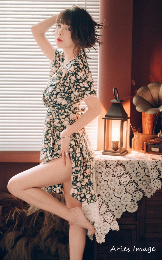 一个穿着连衣裙的年轻女子 双腿交叉站在床上。