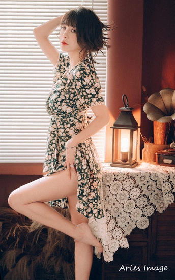 一个穿着连衣裙的年轻女子 双腿交叉站在床上。