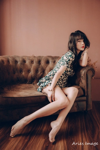 一个穿着连衣裙的年轻女子坐在沙发上 双腿交叉。