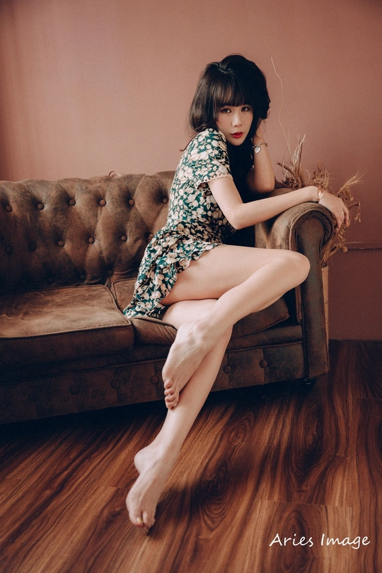 一个穿着连衣裙的年轻女子坐在沙发上 双腿交叉。