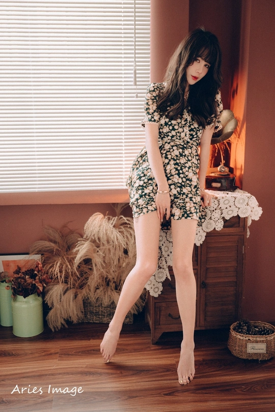 一个穿着连衣裙和高跟鞋的年轻女子站在一个房间里的一张床上。