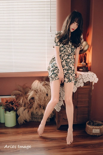 一个穿着连衣裙和高跟鞋的年轻女子站在一个房间里的一张床上。