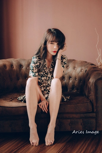 一个穿着连衣裙的年轻女子坐在沙发上 双腿交叉。