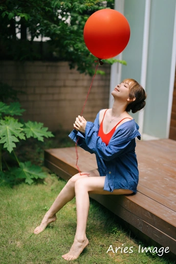 一位年轻女子坐在长凳上抱着一个红气球