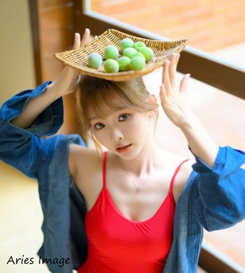 一位穿着红衣服的年轻女子头顶着一个装满鸡蛋的篮子和一个放满水果的盘子。