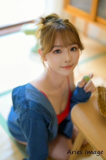 一位穿着蓝色衬衫的年轻女子坐在木制桌子前为相机摆姿势