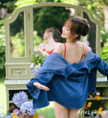 一位穿着蓝色连衣裙的年轻女子站在镜子前