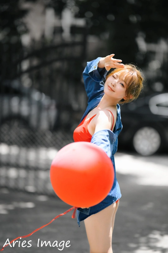 空中握着红气球的一名年轻女子