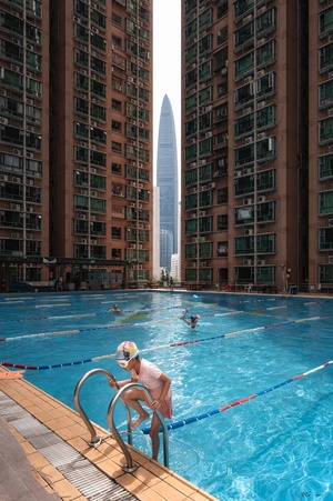 一个人和一个女人在一个城市的游泳池里游泳 背景是建筑物。