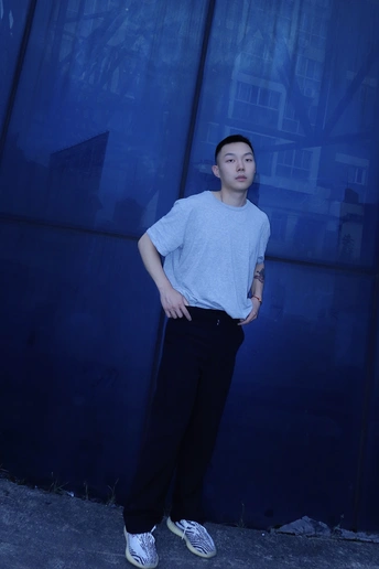 一个年轻人站在一栋楼前的蓝墙前