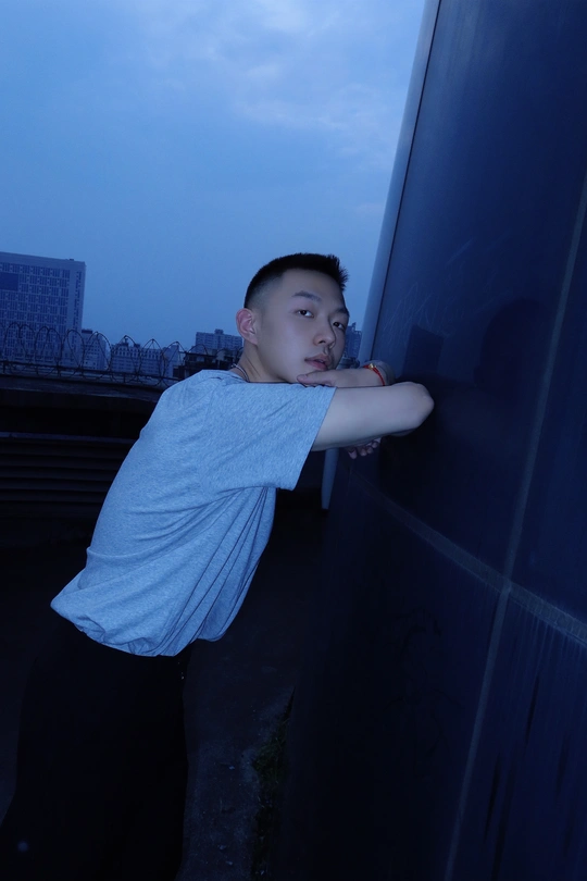 一个年轻人靠在墙上 晚上从窗户向外看