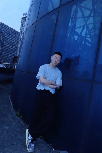 一个年轻人靠在建筑物旁边的蓝墙上