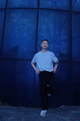 一个年轻人站在一堵蓝墙前