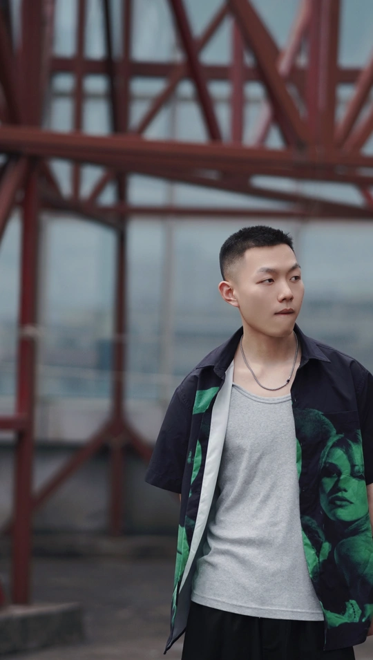 一个穿着黑白夹克的年轻人站在一座桥前