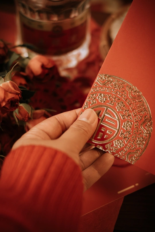 一位女士拿着一个红 envelope 和一张卡片和花