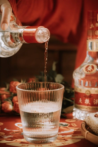 一个人从瓶子里倒饮料到玻璃杯里