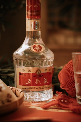 一瓶伏特加酒正坐在桌子旁边的一个玻璃杯上。
