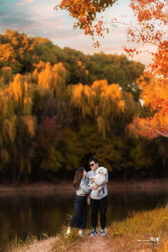 年轻夫妇抱着一只泰迪熊站在湖或河的前面