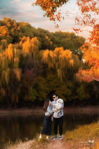 年轻夫妇抱着一只泰迪熊站在湖或河的前面