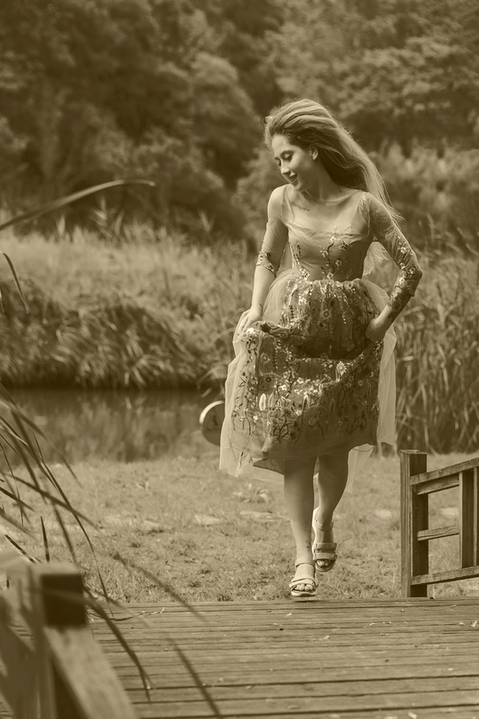 一个穿着连衣裙的年轻女子沿着湖上的木桥行走