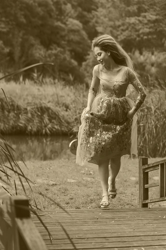 一个穿着连衣裙的年轻女子沿着湖上的木桥行走