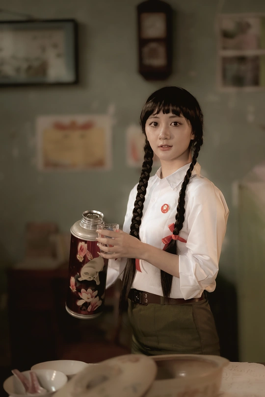 一个年轻的女人 一手拿着杯子 另一只手拿着一罐茶 站在一张桌子前