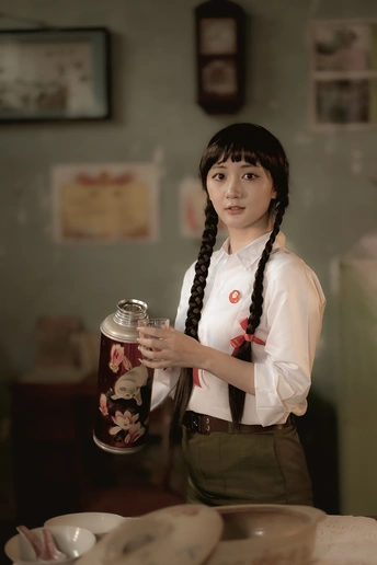 一个年轻的女人 一手拿着杯子 另一只手拿着一罐茶 站在一张桌子前