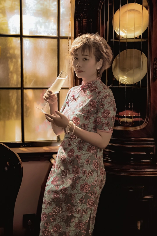 一个穿着连衣裙的年轻女子站在窗前 手里拿着一杯香槟