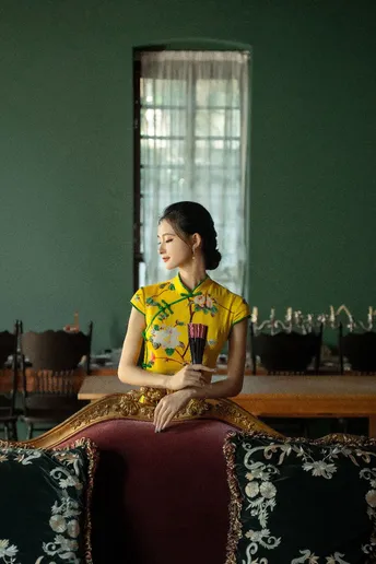 一位穿着黄色衬衫的年轻女子坐在一个有桌子和椅子的房间里。