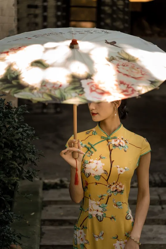 一位穿着黄色连衣裙的年轻女子手持花伞