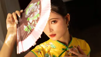 一位穿着黄色连衣裙的年轻女子拿着粉色雨伞