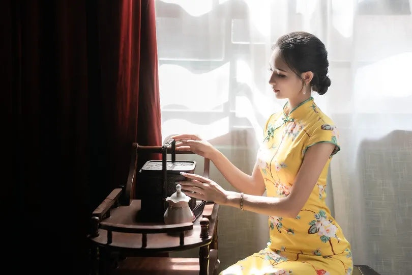 一个穿黄裙子的年轻女子在窗户边弹钢琴