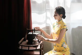 一个穿黄裙子的年轻女子在窗户边弹钢琴
