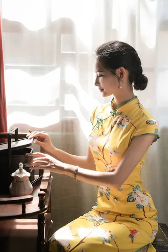 一个穿黄裙子的年轻女子在弹钢琴