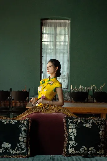 一位穿着传统黄色连衣裙的年轻女子坐在一个有镜子的房间里 桌子上放着一张桌子。