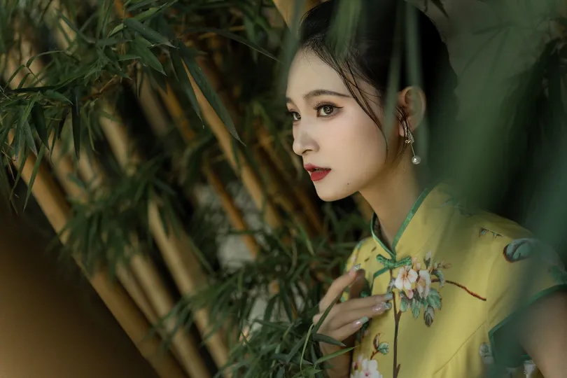 一位穿着黄色衬衫的年轻女子站在一堵绿色植物墙和一把雨伞前面