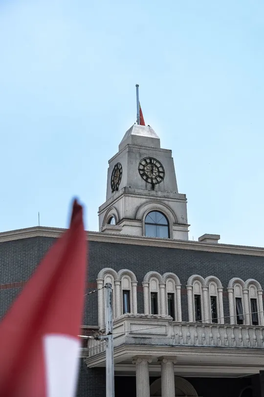 一座高大的建筑 顶部有大型钟楼和一面飘扬的国旗