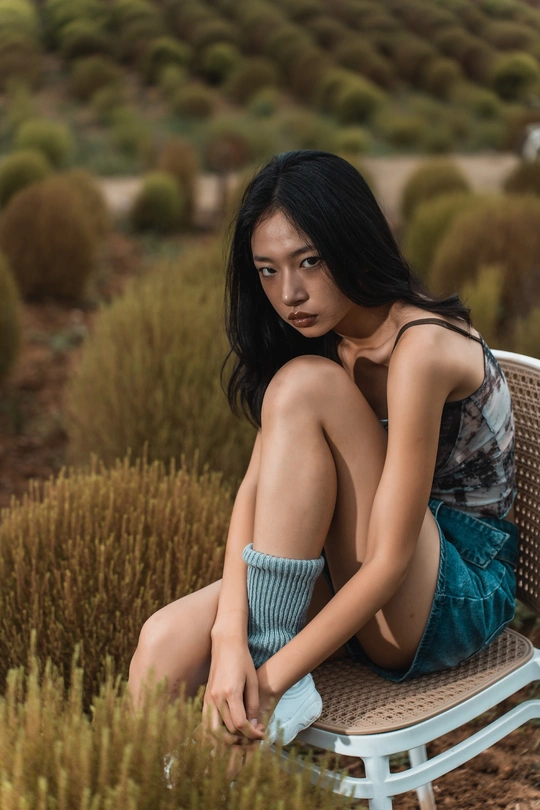 一个美丽的年轻女子坐在蓝色的椅子上 在花园中摆姿势。