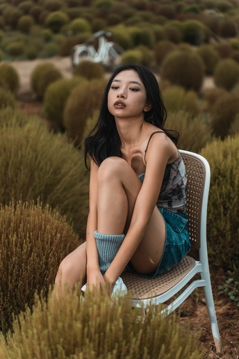 一位坐在灌木丛中的蓝色椅子上美丽年轻的女子