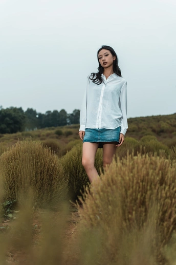 一位穿着蓝色衬衫的年轻女子站在一片草地上