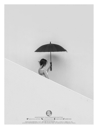 一个人站在楼梯上 手里拿着一把黑白色调的伞 背景是白色墙壁。