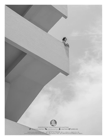 一个人站在一栋高楼的顶部 天空中有一只风筝在飞翔。