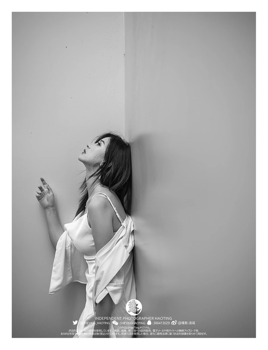 一位穿白衬衫的女性靠在墙上 手举向天空