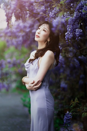 怀孕的妇女穿着蓝色裙子站在紫花前面