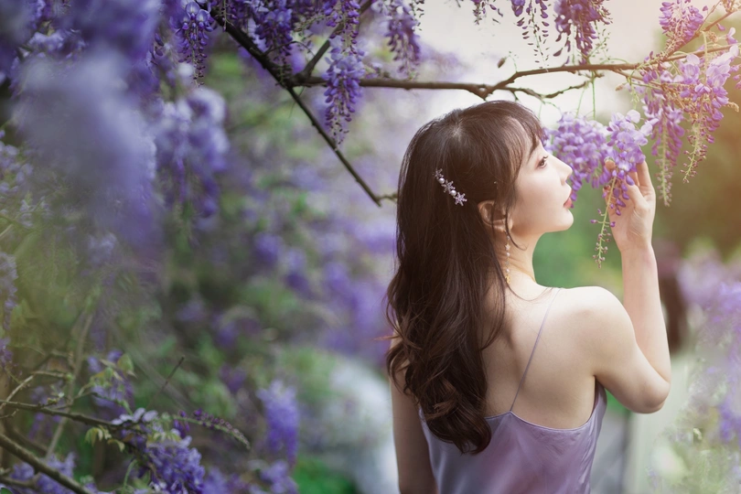 一位穿着紫色裙子的美丽年轻女子抱着紫色花