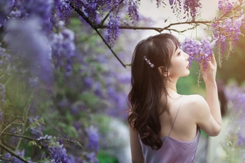 一位穿着紫色裙子的美丽年轻女子抱着紫色花