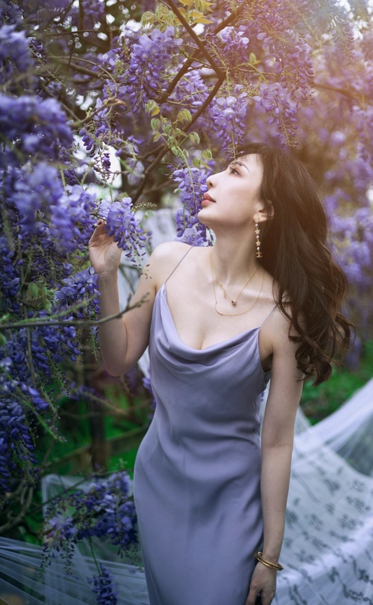 一位穿着蓝色连衣裙的美女站在一个被紫花环绕的花园里
