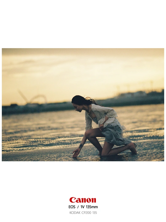 一个年轻女子跪在水边的海滩上