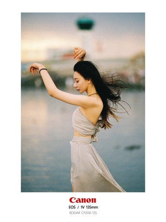 一个穿着白色连衣裙的年轻女子在水体附近扔飞盘