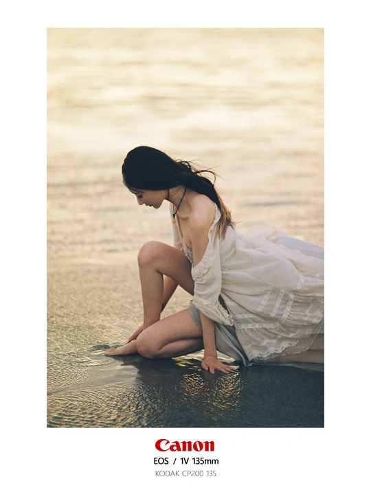 一个穿着白色连衣裙的年轻女子坐在海滩的沙滩上